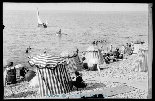 Foule sur les galets, avec barques (vue de la)