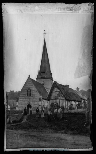 Eglise et d'habitations avec des personnages dont le curé. Sur une petite pancarte est indiqué chemin vicinal de grande circulation n°127-1 (vue d'une)