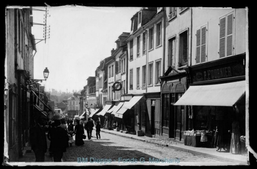 Rue avec « Bonneterie P. Fournier », « Bazar Parisien », « Hôtel du Grand Cerf », « Pharmacie L. Lévèque »... (vue d'une)